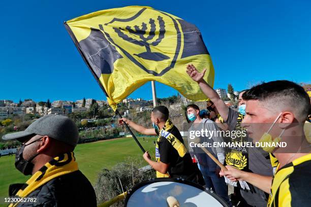 Fans of Israeli Beitar Jerusalem football club show their support during the team's training in Jerusalem on December 11 after a member of Abu...