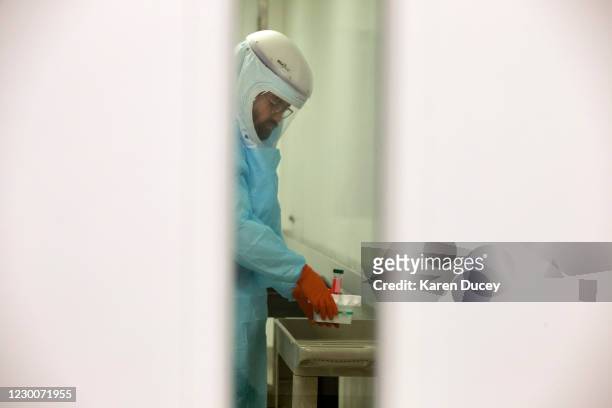 Wearing a powered air-purifying respirator research scientist Dr. Jesse Erasmus takes diluted serum samples into a Biosafety level 3 lab at the...