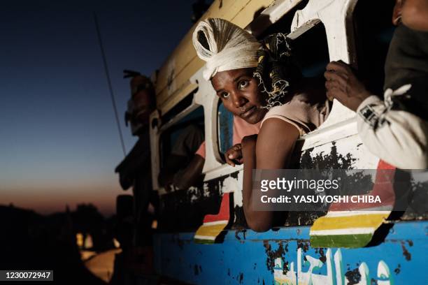 Ethiopian refugees who fled Ethiopia's Tigray conflict arrive by bus from Village Eight transit centre near the Ethiopian border at the entrance of...