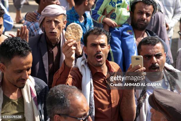 Yemeni man holds up a piece of bread during a demonstration against the deteriorating economic situation in Yemen's third city of Taez on December...