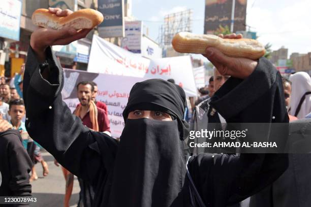 Yemeni woman holds up loaves of bread during a demonstration against the deteriorating economic situation in Yemen's third city of Taez on December...