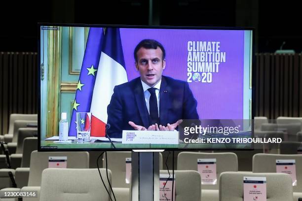 French President Emmanuel Macron appears on a screen to deliver a speech during the Climate Ambition Summit 2020 in Brussels on December 12, 2020 as...