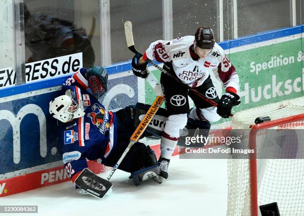 Goalkeeper Andreas Jenike of Iserlohn Roosters and Alexander Oblinger of Koelner Haie battle for the puck during the Ice Hockey Test Match between...