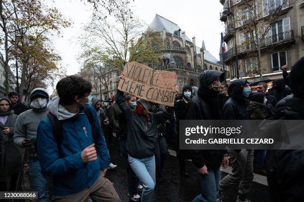 Protester holds a sign reading 'Police and sociale violence, same struggle' during a demonstration in Paris on december 12 against the 'global...