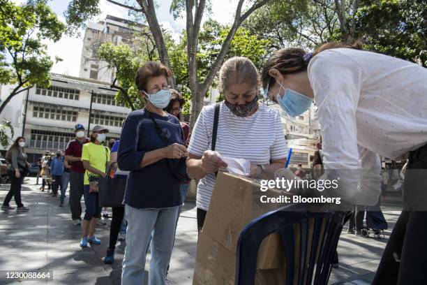 People wearing protective masks stand in line to vote during an opposition-led plebiscite in the Chacao neighborhood of Caracas, Venezuela, on...