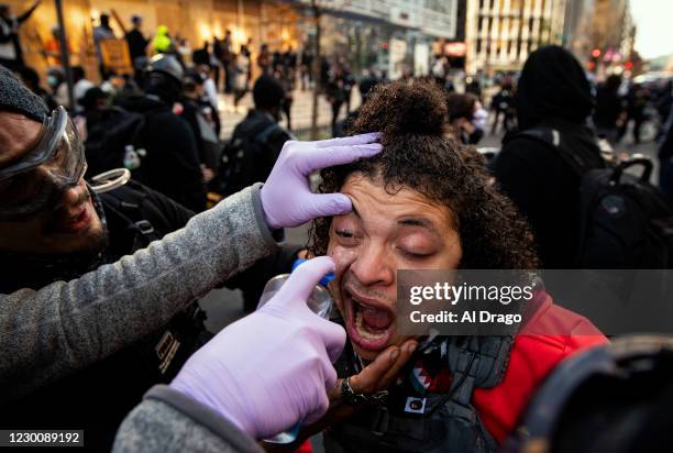 Counter-protester has his eye cleaned after a chemical was sprayed in the air, as supporters of President Trump protest the 2020 presidential...