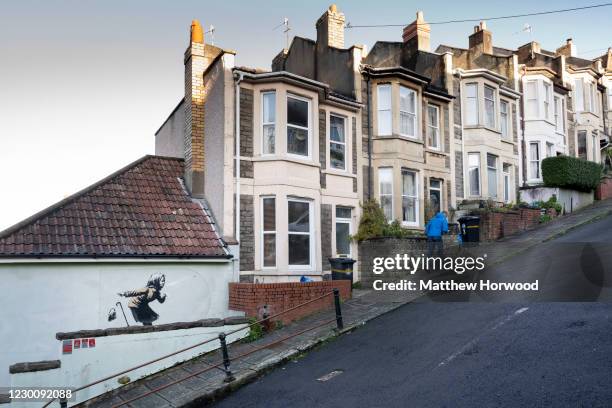 Man walks away from artwork by Banksy on December 12, 2020 in Bristol, England. Banksy claimed the artwork "achoo" as his in a tweet after it...