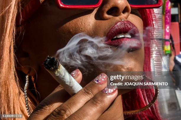 Woman smokes a joint during a rally demanding the decriminalization of marijuana in Medellin, Antioquia department, Colombia on December 12, 2020.