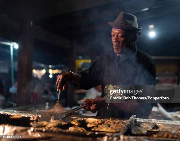George Haynes, known locally as 'Uncle George' cooking fish on a barbeque at the traditional Friday night Fish Fry at Oistins on the South Coast of...