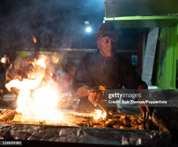 George Haynes, known locally as 'Uncle George' cooking fish on a barbeque at the traditional Friday night Fish Fry at Oistins on the South Coast of...