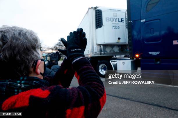 Susan Deur cheers as trucks carrying the first shipment of the Covid-19 vaccine that is being escorted by the US Marshals Service, leave Pfizer's...