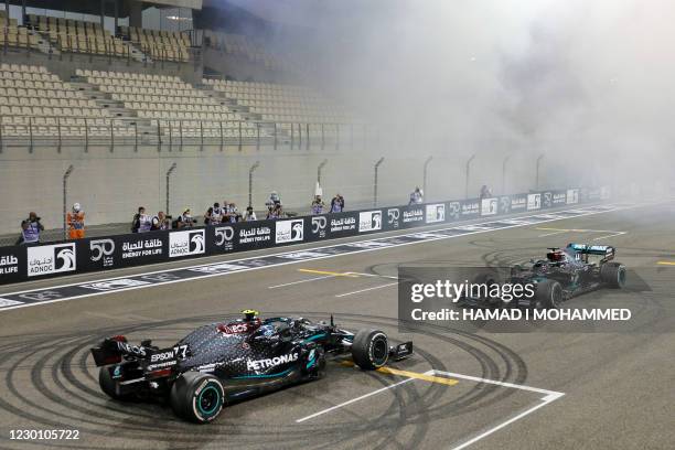 Mercedes' Finnish driver Valtteri Bottas and Mercedes' British driver Lewis Hamilton do doughnuts after the Abu Dhabi Formula One Grand Prix at the...