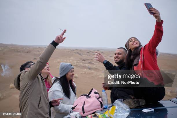 Iranian youth take a selfie as they stand on a sandy hill in Khatabshekan desert in Aran-va-Bidgol county in Isfahan province about 320km south of...