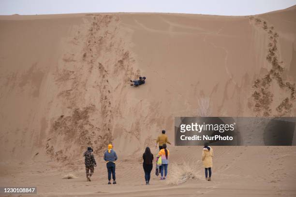 An Iranian woman rolls down from top of a sandy hill in Khatabshekan desert in Aran-va-Bidgol county in Isfahan province about 320km south of Tehran...