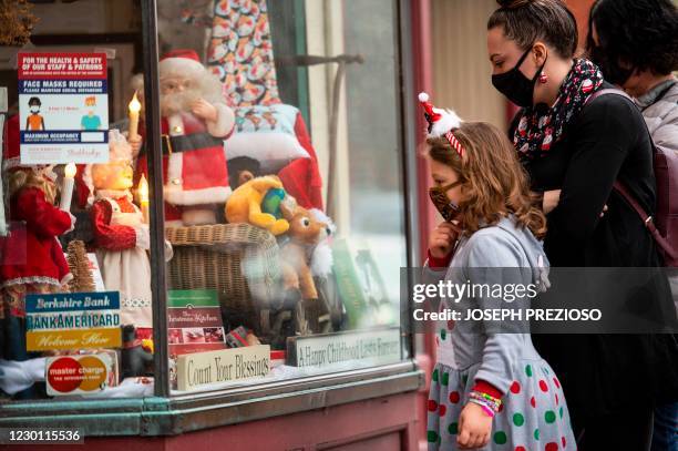 People look at the holiday decorations in the window displays at the Country store on Main Street in Stockbridge, Massachusetts on December 13, 2020....