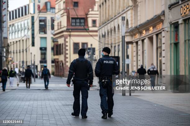 Police officers patrol through the almost deserted shopping streets in the city center in Leipzig, eastern Germany on December 14, 2020 amidst the...