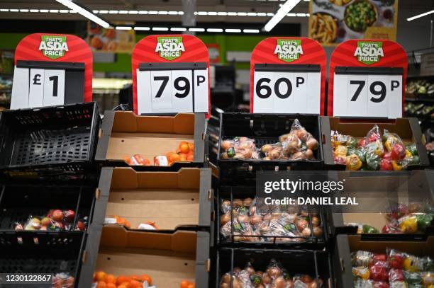 Labels show the prices of fresh fruit and vegetables displayed for sale in an Asda supermarket in London on December 14, 2020. - With just over two...