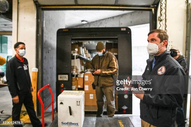 Kentucky Governor Andy Beshear speaks to the media as Byron Bishop , a UPS driver, scans a delivered COVID-19 vaccination package in a loading dock...