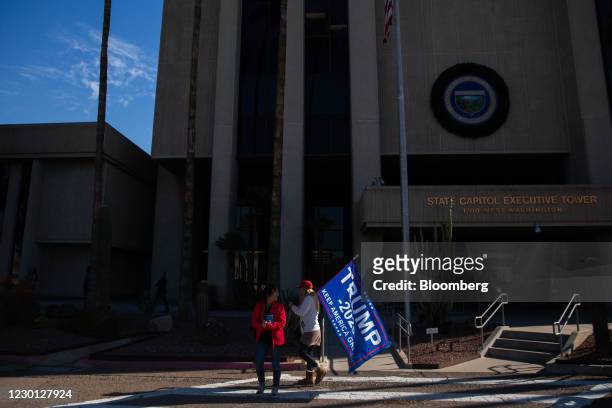 Demonstrator holds a "Trump 2020" flag outside the Arizona State Capitol on Monday, Dec. 14, 2020. Members of the Electoral College meet on Monday to...