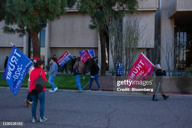 Demonstrators hold "Trump 2020" flags outside the Arizona State Capitol on Monday, Dec. 14, 2020. Members of the Electoral College meet on Monday to...