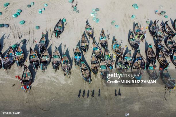 In this aerial photograph taken on October 7 members of the Rapid Action Battalion walk past fishing boats while on patrol along a beach in Shamlapur...