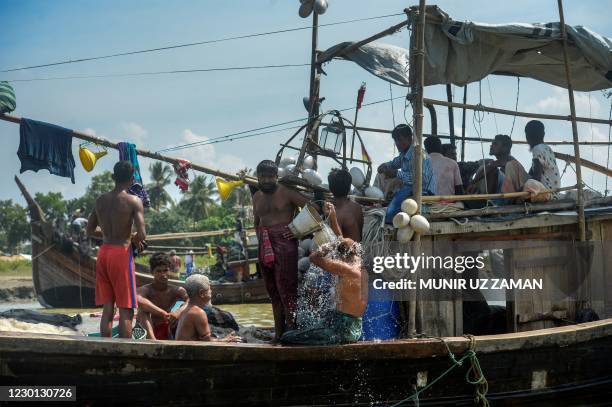 This photograph taken on October 9 shows a fisherman taking bath as others rest near a fish market ghat, a pick up point for Rohingya refugees...