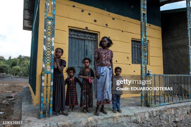 Woman and her children stand in front of their damaged house in the village of Bisober in Ethiopia's Tigray region, on December 9, 2020. - The...