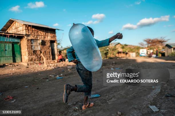 Boy runs with a balloon in the village of Bisober, in Ethiopia's Tigray region on December 9, 2020. - The November 14 killings represent just one...