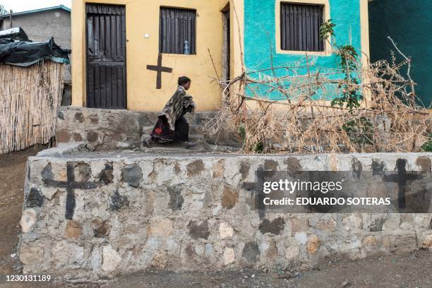 Child runs past houses whose walls are covered with crosses, in the village of Bisober, in Ethiopia's Tigray region on December 9, 2020. - The...