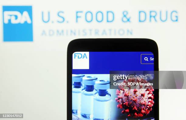In this photo illustration, Food and Drug Administration of the United States webpage and vials seen displayed on a mobile phone screen in front of...