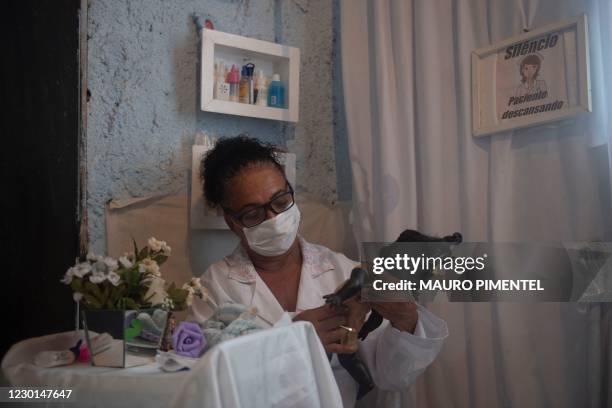 Suelen da Silva -who lost her job in April, shortly after the coronavirus pandemic arrived in Brazil- checks a doll at her 'Doll Hospital' located in...