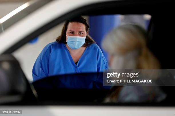 Dis-Chem Pharmacy health professional speaks to a woman before conducting a COVID-19 coronavirus test at a drive-through testing site at a mall in...