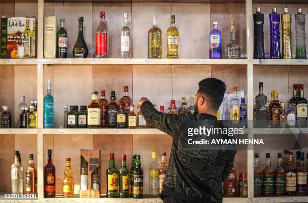Shopworker arranges whisky bottles on a shelf at a liquor shop in the Bataween district in the centre of Iraq's capital Baghdad on December 5, 2020....