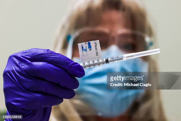 Rocky Mountain Regional VA Medical Center registered nurse Patricia Stamper looks at a dose of the Pfizer-BioNTech COVID-19 vaccine before...