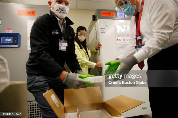 Luca Cattaneo, Registered Pharmacist at Beth Israel Deaconess Medical Center hands off a box containing the Pfizer/BioNTech vaccine to Gordon Hubbard...