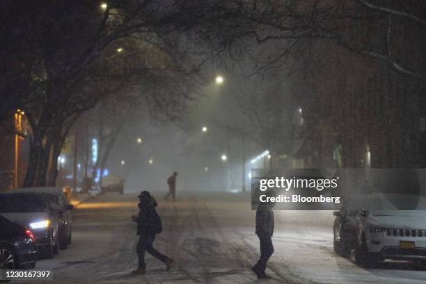 Pedestrians cross a street as snow falls in New York, U.S., on Wednesday, Dec. 16, 2020. A major winter storm is zeroing in on more than 51 million...