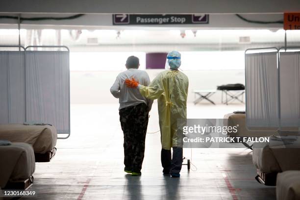 Nurse supports a patient as they walk in the Covid-19 alternative care site, built into a parking garage, at Renown Regional Medical Center, December...