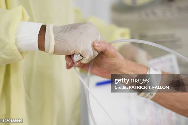 Doctor holds a patient's hand in the Covid-19 alternative care site, built into a parking garage, at Renown Regional Medical Center, December 16,...