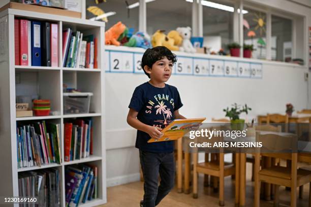 In this photograph taken on September 23 five year old Adam carries a book in a classroom at his school in Duiven, The Netherlands. - In 2015, with...