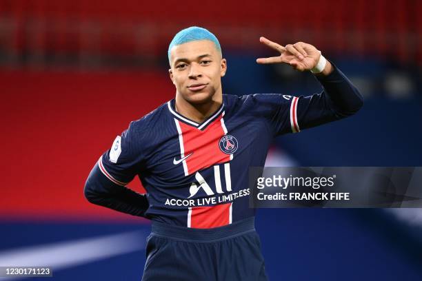 Paris Saint-Germain's French forward Kylian Mbappe, with blue hair, flashes the "V" for victory, during the French L1 football match between...