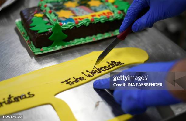 Baker cuts out the lettering 'Merry Christmas' for a cake decoration at Schuerener Backparadies bakery in Dortmund, western Germany, on December 17,...
