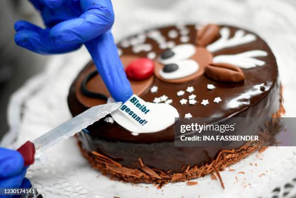 Baker places a sign 'Stay healthy' on a cake with Rudpolh, the Red-Nosed reindeer, at a bakery in Dortmund, western Germany, on December 17, 2020...