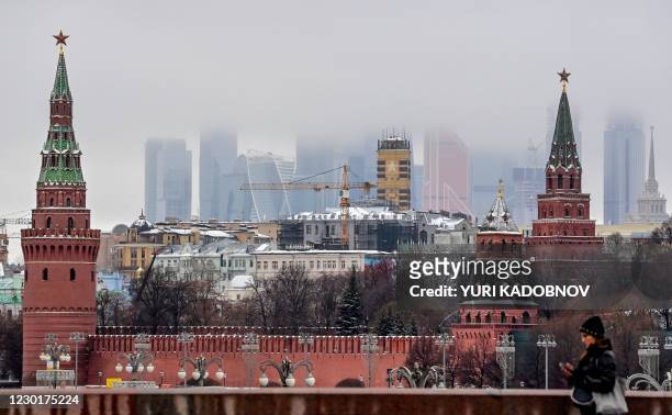 Woman walks in front of the Kremlin and skyscrapers of the Moscow International Business Centre in Moscow on December 17, 2020.
