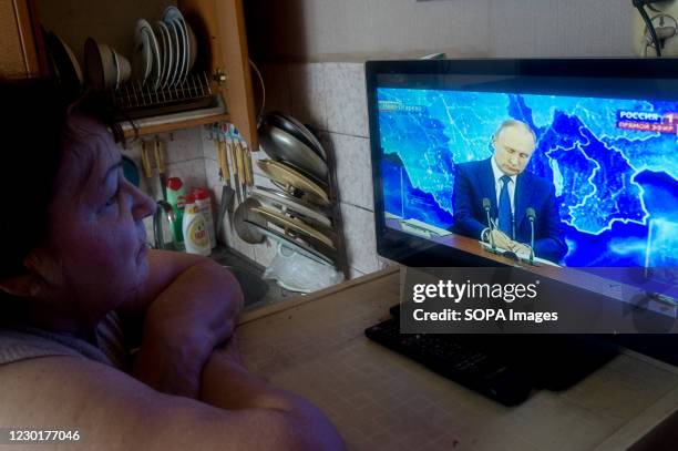 An elderly woman watches the live broadcast of the annual press conference of Russian President Vladimir Putin on TV from her apartment in Tambov....