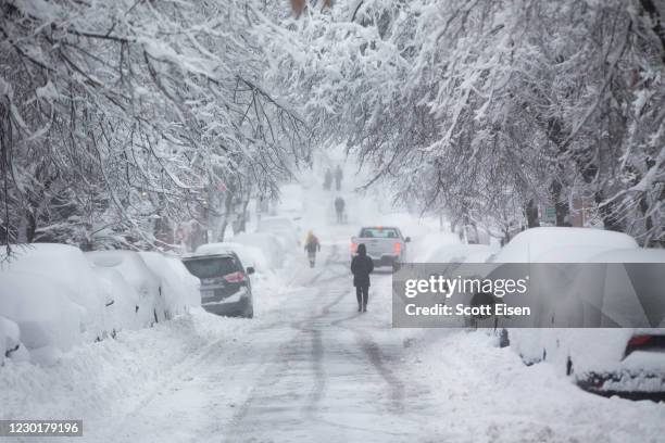 People walk down a snow-covered Chestnut Street on December 17, 2020 in Boston, Massachusetts. More than a foot of snow is expected in the Greater...