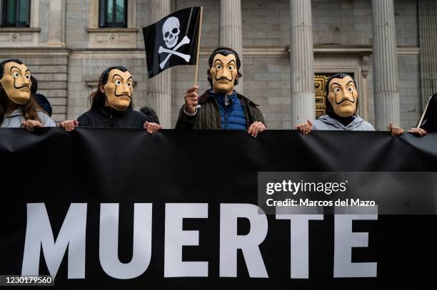 Protesters wearing face masks of Dali carrying a flag with skull during a demonstration against euthanasia in front of the Spanish Parliament as it...