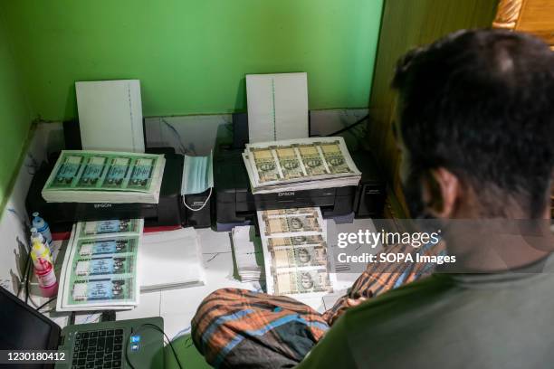 Gang member Zakir Hossain displays the fake currency notes next to a laptop computer in Dhaka. Police recently raided a fake currency-making gang in...