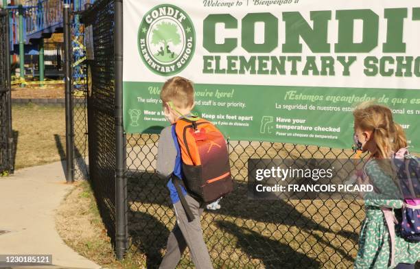 School children wearing facemasks walk outside Condit Elementary School in Bellaire, outside Houston, Texas, on December 16, 2020. - The coronavirus...