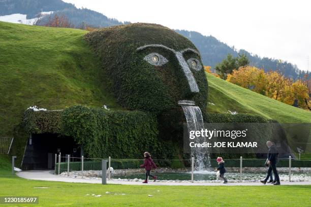 Visitors walk around a pond at the Swarovski Crystal Worlds museum and park, near the plant of Austrian crystal glass manufacturer Swarovski in...