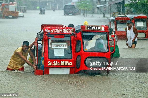 People push a half-submerged tricycle through a flooded street due to heavy rains caused by tropical depression Vicky in San Francisco town, Agusan...